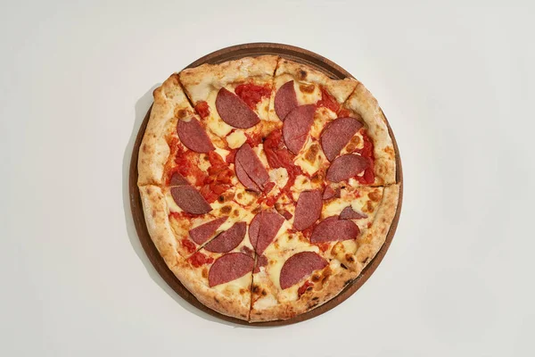 Vista superior de corte sabrosa pizza en tablero de madera círculo — Foto de Stock