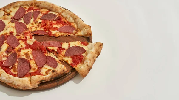 Parcial de pizza con rebanada cortada sobre tabla de madera — Foto de Stock