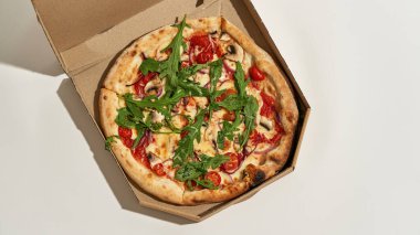 İçinde çeşitli malzemelerden yapılmış pizza olan karton bir kutu.