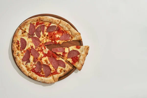 Pizza de pepperoni con rebanada cortada sobre tabla de madera — Foto de Stock