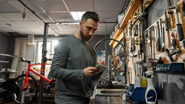 Cycling service man writing notes in workshop