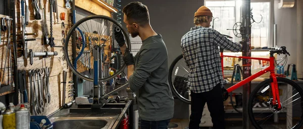 Two cycling mechanics working in bicycle workshop