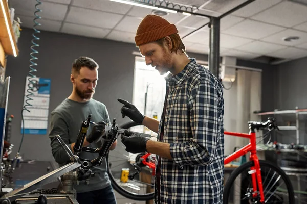 男は同僚測定自転車フォークのメモを書きます — ストック写真