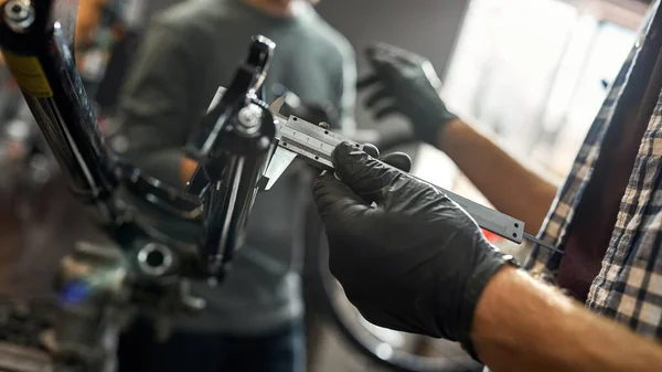 男性技術者はキャリパーで自転車フォークを測定します — ストック写真
