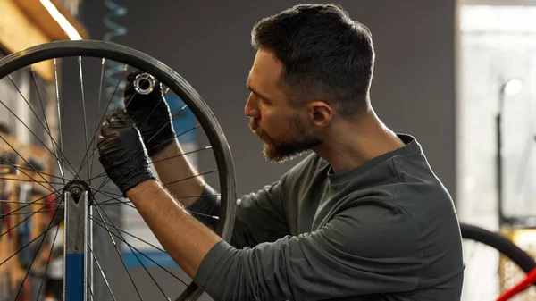 Serviceman checking bicycle wheel spoke with key