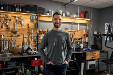 Atölyede elleri ceplerinde bisiklet tamircisi