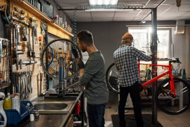 Bisiklet atölyesinde çalışan iki tamirci.