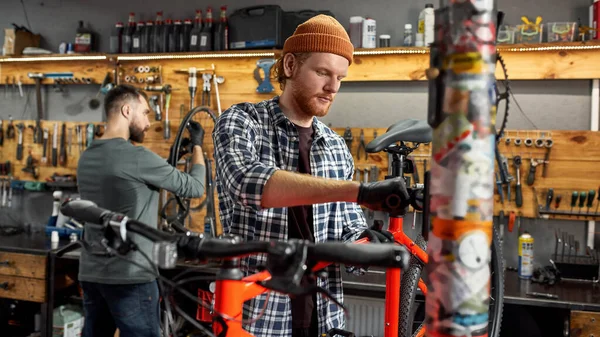 Mechanic fix bicycle seat and man check bike wheel