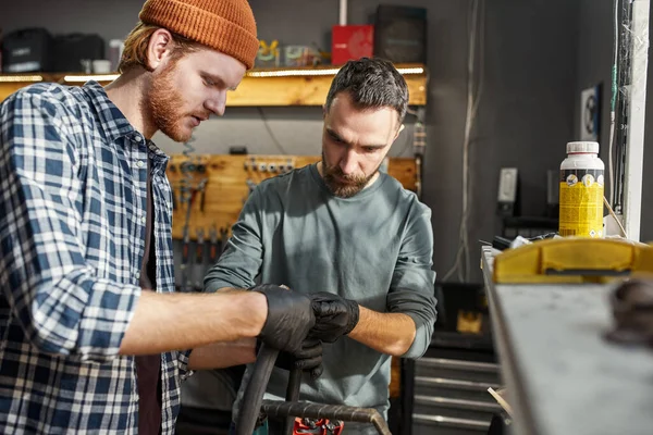 Two repairmen glueing bicycle patch on bike tube