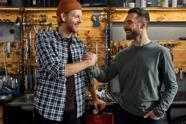 Junge Reparateure beim Händeschütteln in Fahrradwerkstatt — Stockfoto