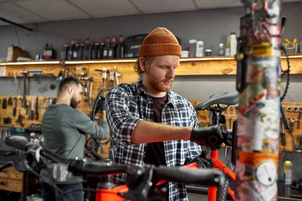 Cykelmekaniker fixa cykelsäte nära kollega — Stockfoto