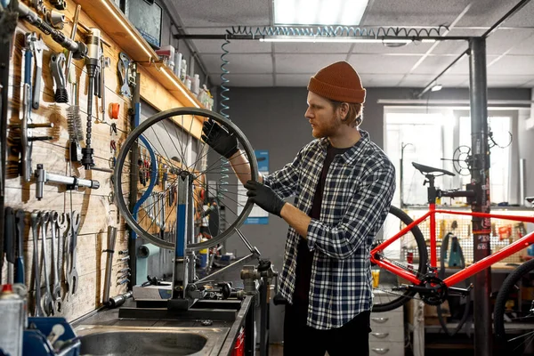 修理工の横ビューチェック自転車ホイールが話しました — ストック写真