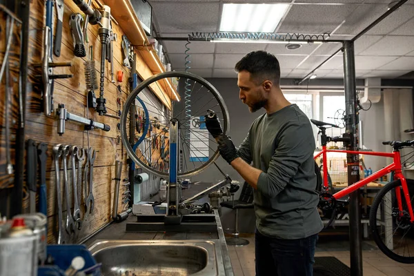 Side view of serviceman check bicycle wheel spoke