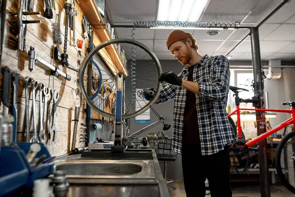 Man checking bicycle wheel spoke with spoke key