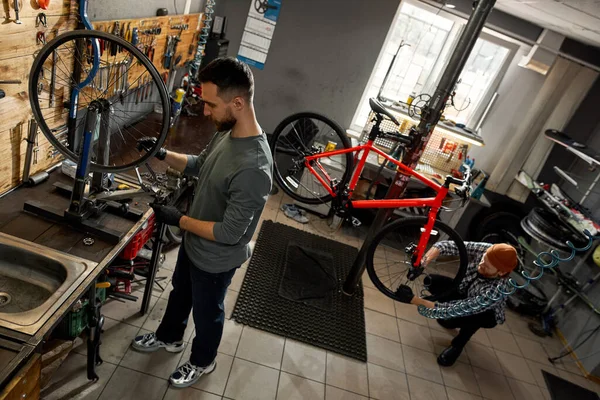 Cycling craftsman repair bike wheel near colleague