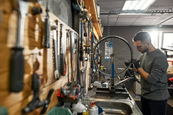 Ung cykel mekaniker kontrollera cykel hjul talade — Stockfoto