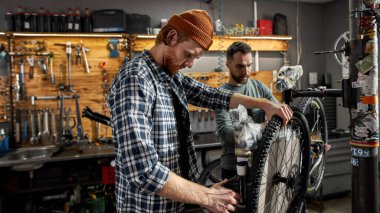İki adam atölyede yeni bir bisiklet monte ediyor.