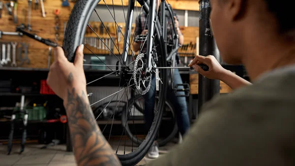 Black woman cycling master fixing wheel on bicycle