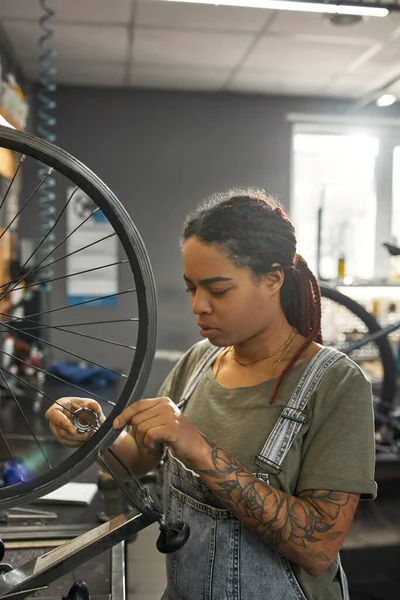 Girl repairman check bicycle wheel spoke with key