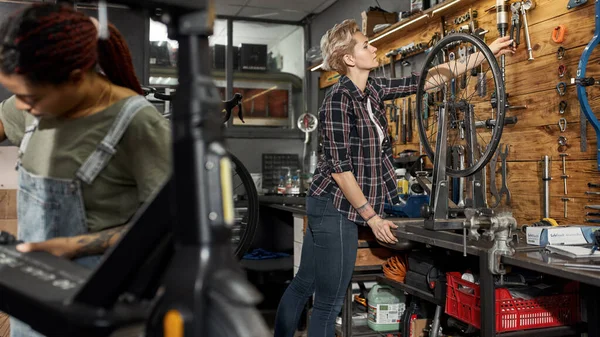 女性の自転車修理工は自転車工場で働く — ストック写真