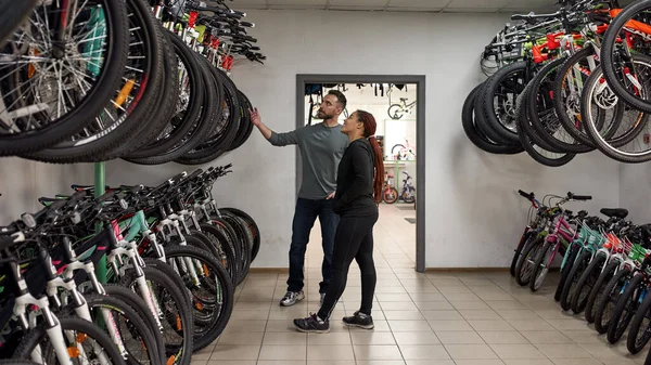 Seller show bicycles for female customer in shop