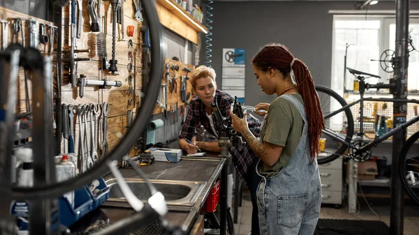 Garota e colega medir garfo de bicicleta com paquímetros — Fotografia de Stock