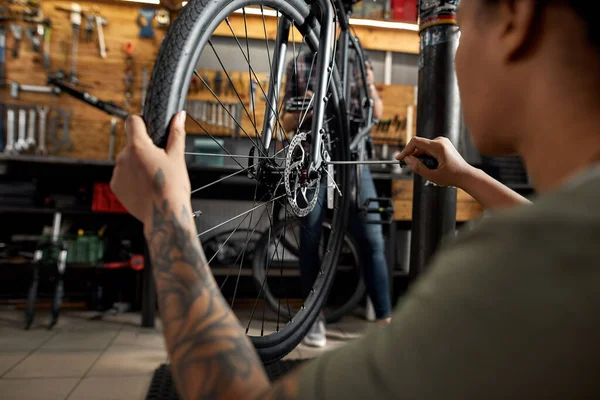 Black girl cycling repairman fix wheel on bicycle