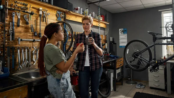 Τα κορίτσια πίνουν καφέ και μιλάνε στο εργαστήριο ποδηλάτων. — Φωτογραφία Αρχείου