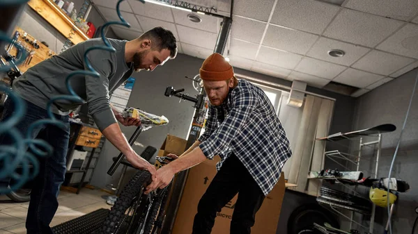 Män montera ny cykel tillsammans i verkstad — Stockfoto