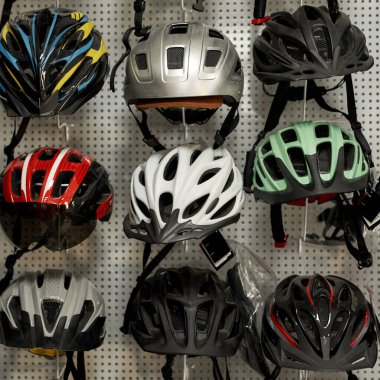Bisiklet dükkanından satın almak için asılan farklı renkte modern bisiklet kaskları. Aşırı spor, kentsel yaşam tarzı, çocuklar, eğlence ve boş vakitlerde korunmak için bisiklet nesneleri