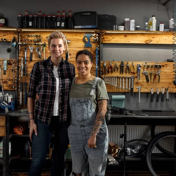Zwei Junge Lächelnde Multiethnische Fahrradmeister Stehen Der Werkstatt Arbeitskolleginnen Umarmen — Stockfoto