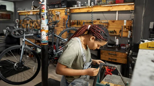 現代の自転車ワークショップで自転車チューブを固定女性サイクリング修理人 若いアフリカ系アメリカ人女性 自転車サービス 修理とアップグレード 設備付きガレージインテリア — ストック写真