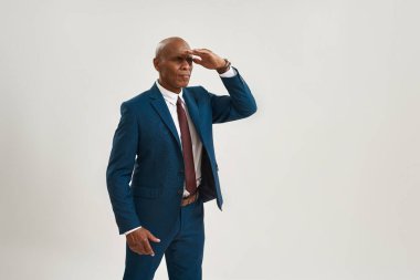 Odaklanmış Afro-Amerikan iş adamı ya da CEO müdürü başka tarafa bakıyor. Takım elbiseli kel bir yetişkin. Modern başarılı erkek yaşam tarzı kavramı. Beyaz arka planda izole edilmiş. Stüdyo çekimi. Boşluğu kopyala