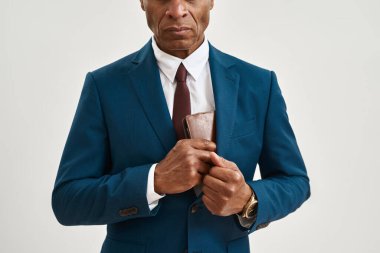 Ciddi bir Afro-Amerikan iş adamının ya da CEO 'nun cüzdanı takım elbisenin cebine koyarkenki görüntüsü. Modern başarılı erkek yaşam tarzı. Beyaz arka planda izole edilmiş. Stüdyo çekimi. Boşluğu kopyala