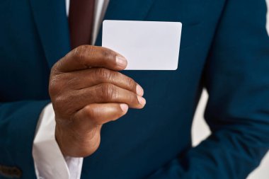 Siyahi iş adamı ya da genel müdürün elindeki kartvizitin seçici odak noktası. Resmi giyinen bir adamın kırpılmış görüntüsü. Modern başarılı erkek yaşam tarzı kavramı