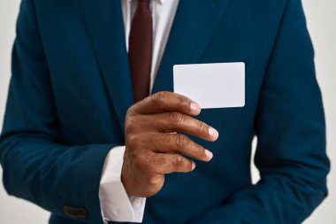 Afrika kökenli Amerikalı girişimci ya da CEO 'nun elindeki kartvizitin seçici odak noktası. Takım elbiseli bir adamın kısmi görüntüsü. Modern başarılı erkek yaşam tarzı kavramı