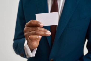 Siyahi iş adamının elindeki kartviziti kapat. Resmi giyinen bir adamın kırpılmış görüntüsü. Modern başarılı erkek yaşam tarzı kavramı. Beyaz arka planda izole edilmiş. Stüdyo çekimi