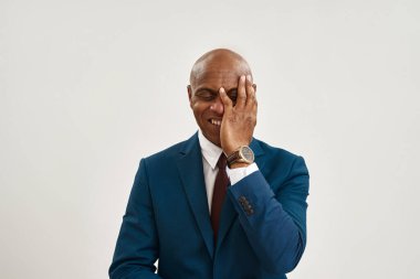 Gülen Afro-Amerikan iş adamının ön yüzü yarım yamalak kapalı gözleriyle ön görüntüsü. Takım elbiseli kel bir yetişkin. Modern başarılı erkek yaşam tarzı. Beyaz arka plan. Stüdyo çekimi. Boşluğu kopyala