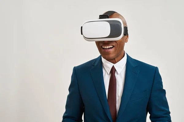 Pleased black businessman using Virtual reality glasses. Bald adult man wearing formal wear. Modern entertainment and leisure. Isolated on white background. Studio shoot. Copy space