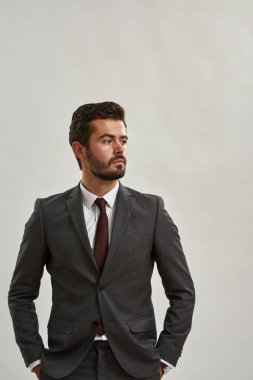 Odaklanmış Kafkas işadamı elleri ceplerinde başka tarafa bakıyor. Resmi kıyafetler giyen sakallı adam. Modern başarılı erkek yaşam tarzı kavramı. Beyaz arka planda izole edilmiş. Stüdyo çekimi. Boşluğu kopyala