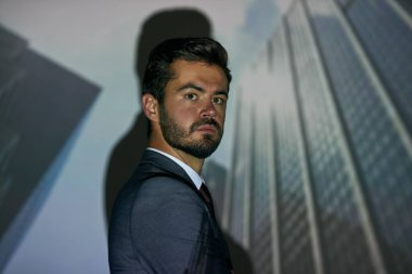 Kentin gökdelenlerinin arka planında kendine güvenen beyaz iş adamı ya da şirket liderinin kırpılmış yan görüntüsü. Resmi giyinmiş bir adam. İş hedefi ve kariyer gelişimi. Modern başarılı erkek yaşam tarzı