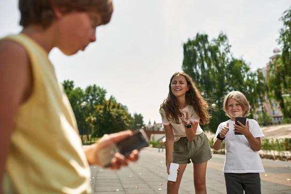 현대의 스마트폰을 아이들은 놀이터에 버튼이 핸드폰을 가지고 혼란에 아이들로부터 웃는다 — 스톡 사진