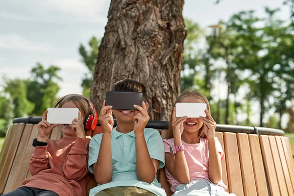 Grupo Crianças Emocionais Usando Assistindo Smartphones Banco Madeira Parque Livre — Fotografia de Stock