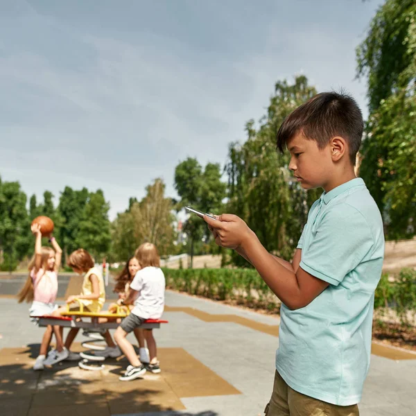 Zaměřte Popředí Osamělé Multiraciální Chlapec Sledovat Smartphone Pozadí Rozmazané Děti — Stock fotografie