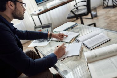 Ofisteki koltukta masada kitaptan notlar yazan zeki, odaklı beyaz bilişim girişimcisi. İş stratejisi, geliştirme, tanıtım, satış, yüksek teknoloji şirketlerinin pazarlanması