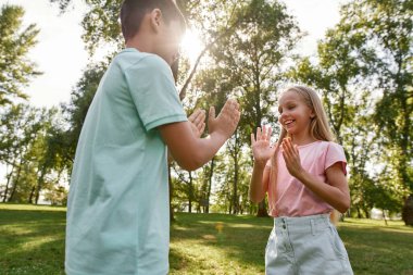 Güler yüzlü beyaz kız ve çoklu etnik çeşitlilikte çocuk açık havada, yeşil çimenlikte birlikte pasta oyunu oynuyorlar. Alfa neslinin sevimli çocukları. Çocukluk yaşam tarzı. Arkadaşlık. Güneşli yaz günü