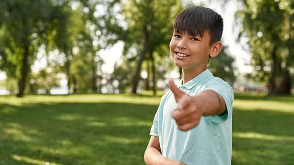 Smiling Multiethnic Boy Pointing Finger Looking Camera Green Lawn Blurred — Stock Photo, Image