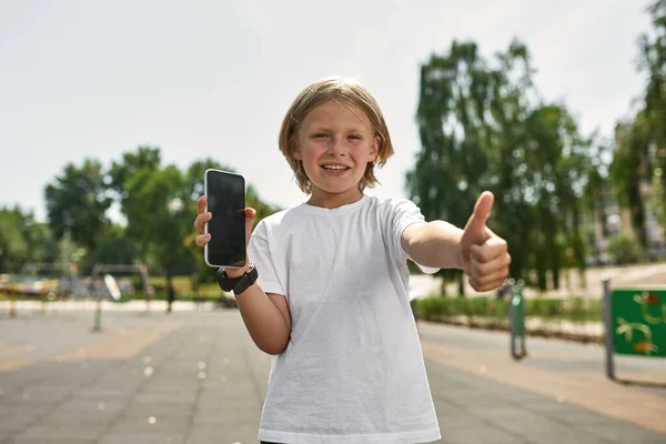 Smilende Kaukasiske Dreng Med Smartphone Show Tommelfinger Kameraet Sløret Legeplads - Stock-foto