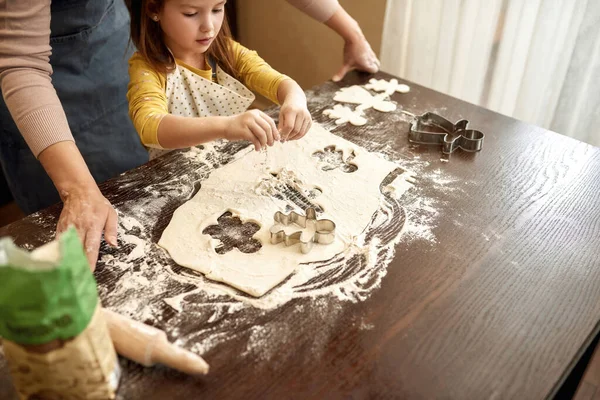 Caucasian little girl pouring flour on dough for cooking cookies with grandmother. Concept of family education and spending time together. Homemade food cooking. Relatives at table at home kitchen
