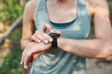 Açık hava spor eğitiminde akıllı yamaç kullanan genç bir sporcunun görüntüsü. Spor giyimli zayıf atletik kız. Modern sağlıklı yaşam tarzı kavramı. Sıcak yaz günü